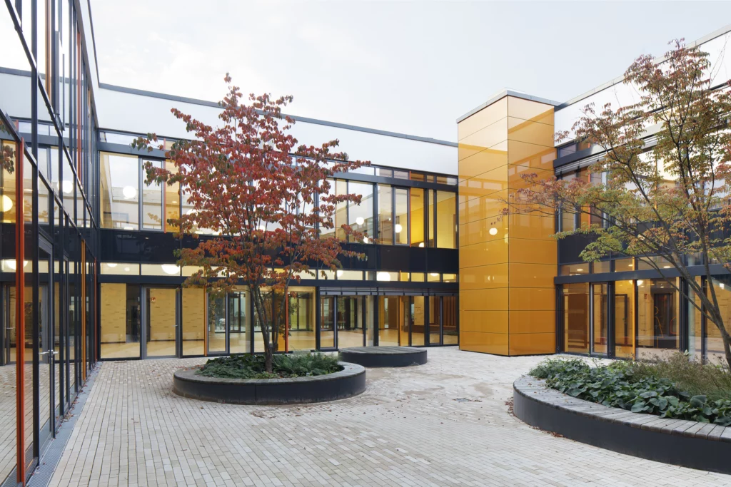 Grundschule auf dem Hagen Foyer Atrium mit Bauminseln Blick zur Aufzugsfassade